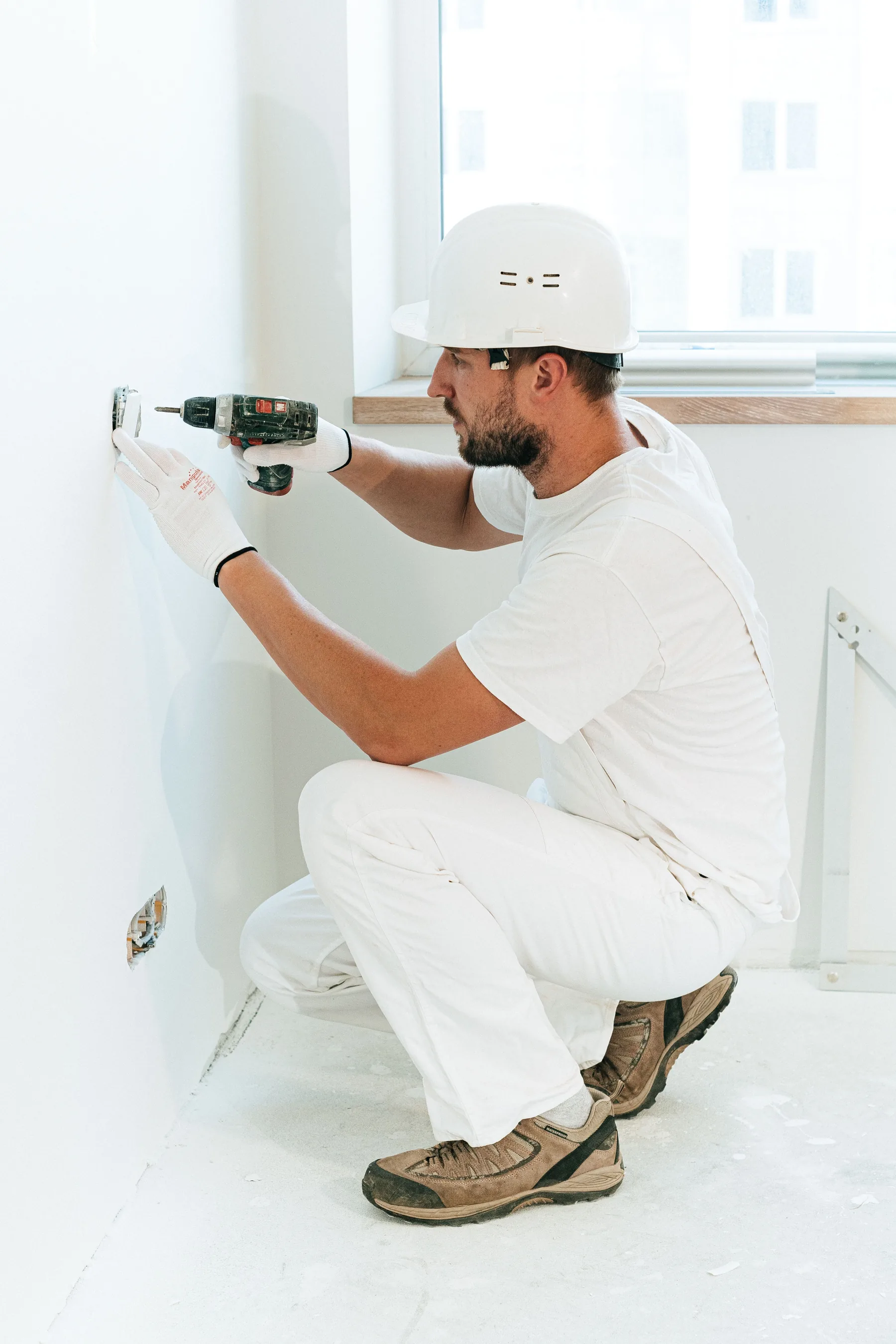 Technician drilling a wall during residential installation work